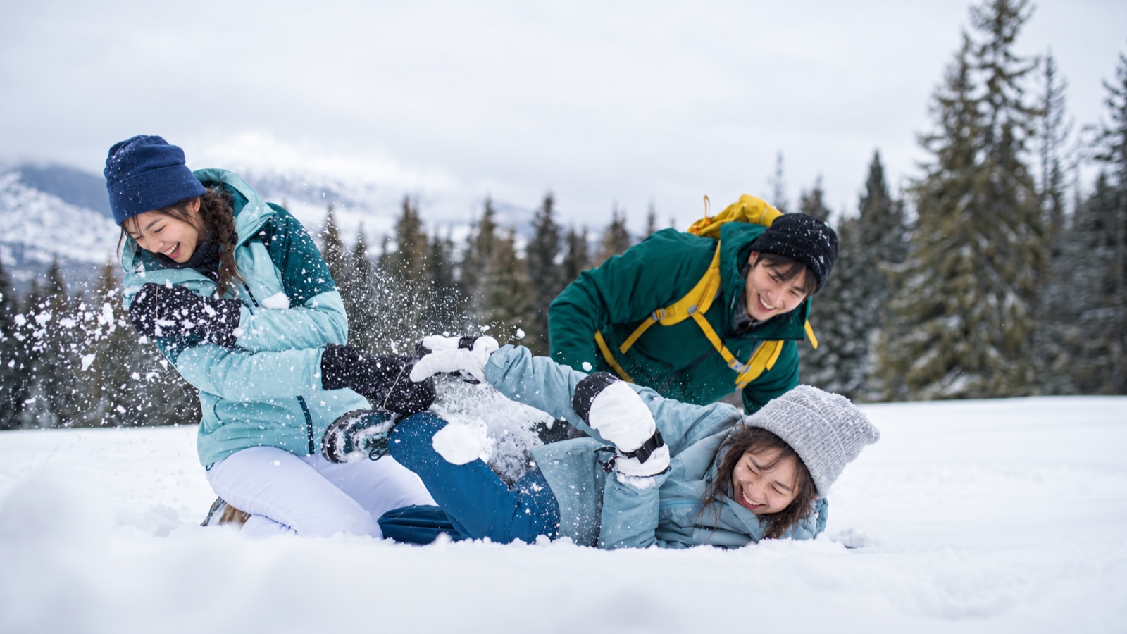 三位朋友在雪地裡嬉笑玩雪